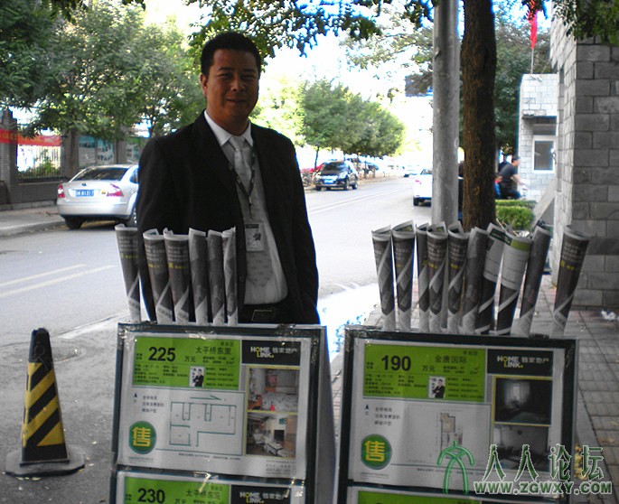 “金九银十”似成梦幻。丰台首科花园小区附近，清闲的房产中介业务员在路旁架起广告牌.jpg